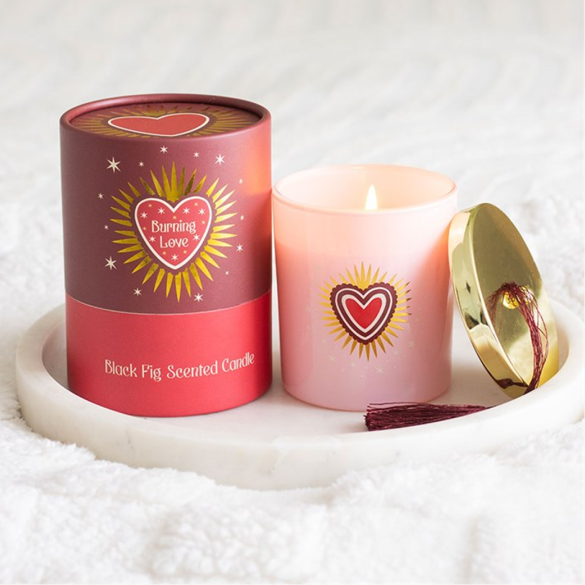 Pink scented candle with a red cylindrical container on a white background