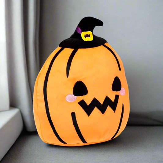 Plush pumpkin pillow with a witch hat on a gray couch