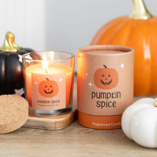 Pumpkin spice candle with packaging and pumpkins on a wooden surface