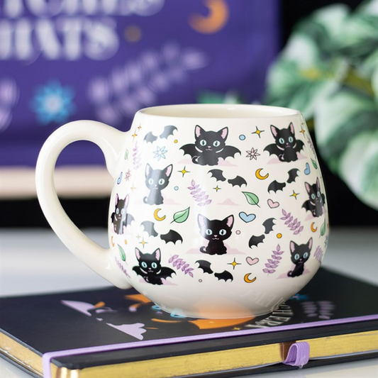 White mug with black cat and bat pattern on a notebook