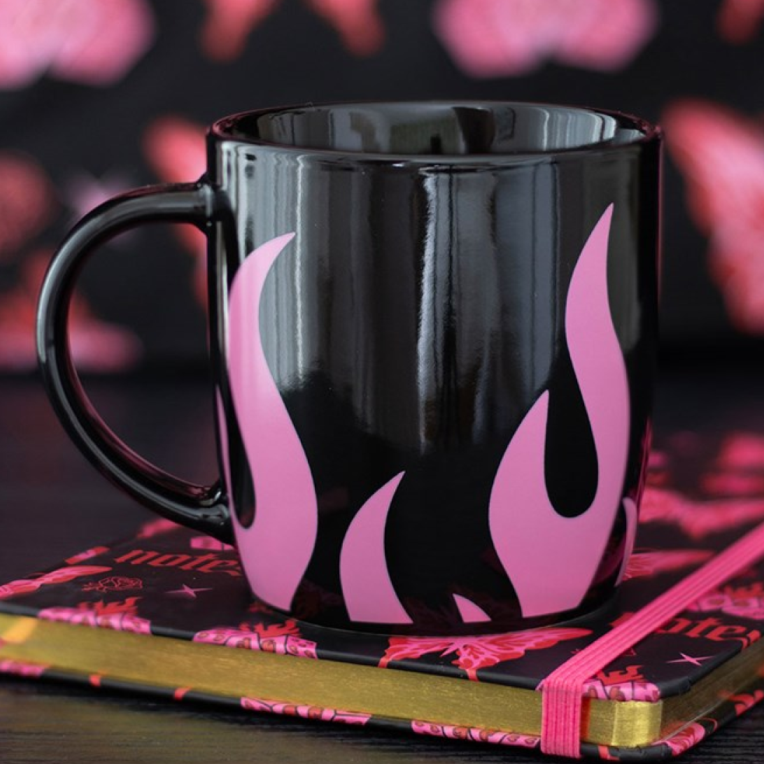 Black mug with pink flames on a notebook against a blurred background