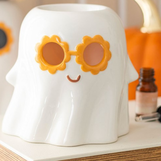 White ghost-shaped container with sunflower sunglasses on a shelf with a pumpkin in the background
